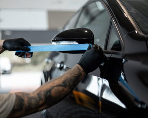 professional-man-tapes-black-car-before-polishing-2024-11-22-02-02-01-utc-scaled.jpg